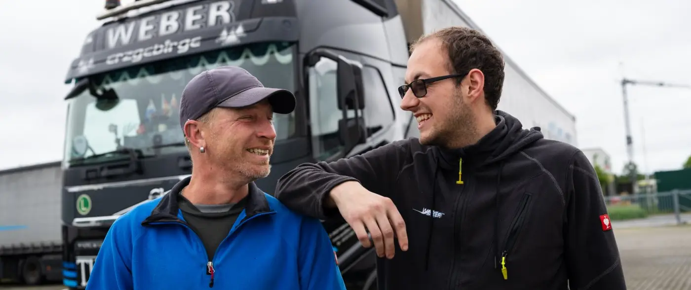 Zwei Kollegen der Spedition Weber im Gespräch vor einem WEBER-LKW